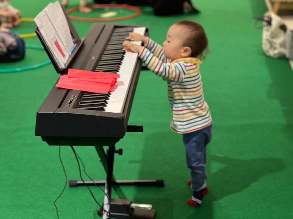 電子ピアノの鍵盤を興味深そうに触っている子どもの写真